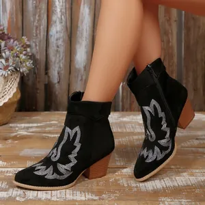 Close-up detail of black Western ankle boots with silver embroidery and chunky high heel