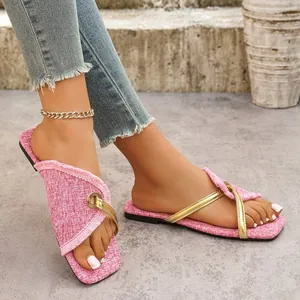 Detailansicht von rosa Tweed-Flachsandalen mit eleganten Goldriemen an den Füßen
