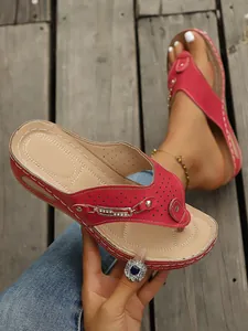 Detalle de chanclas de cuña rojas con hebilla de pedrería y suela beige cómoda