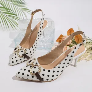 Vista detallada de elegantes zapatos destalonados blancos a lunares con aros dorados