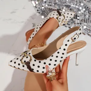Primer plano de tacones destalonados con lunares blancos y hebilla metálica decorativa.