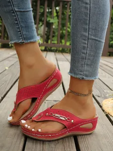 Primer plano de sandalias rojas con cuña, hebilla de metal y detalles de recortes de moda
