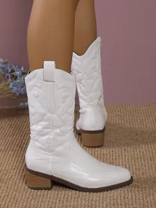 Detailed shot of white western mid-calf boots with embroidery and chunky wooden heels