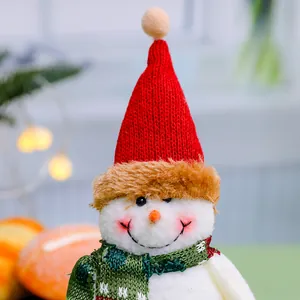 Close-up shot of a cute Christmas snowman plush toy wearing a red knitted hat and scarf