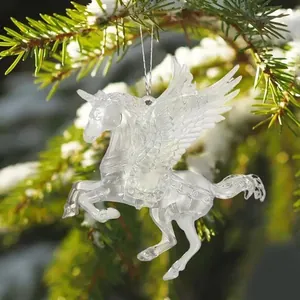 Detailansicht eines transparenten Acryl-Einhorns als Weihnachtsbaumschmuck im Schnee.