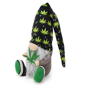 Dettaglio di uno gnomo di peluche con motivo a foglia di cannabis che tiene una foglia verde