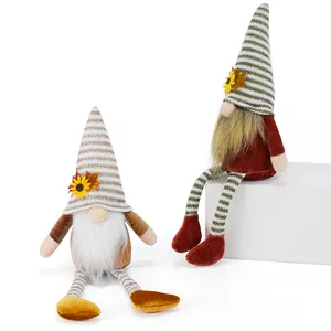 Close-up of autumn faceless gnomes with striped hats and hanging legs decoration
