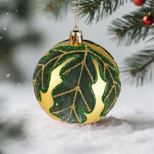 Elegante pallina di Natale dorata da 8cm con motivo a foglie glitterate verdi sulla neve
