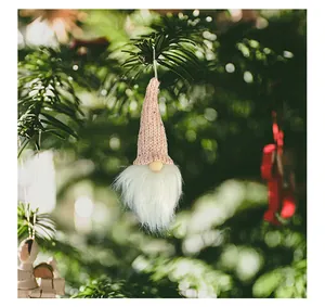 Detailed close-up of a pink knitted hat Christmas gnome hanging on a tree branch.