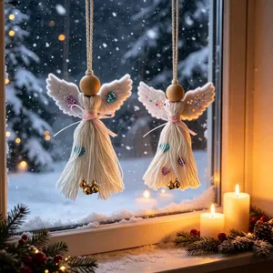 Gros plan d'anges de Noël blancs tissés à la main suspendus à une fenêtre enneigée