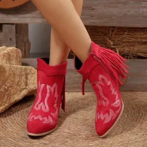 Detailed view of red suede Western ankle boots featuring embroidery and fringes.
