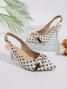 Detalle de zapatos slingback de punta fina con lunares negros y anillos dorados.