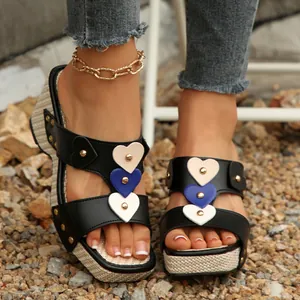Primer plano de sandalias playeras con plataforma, corazones de colores y tachuelas.