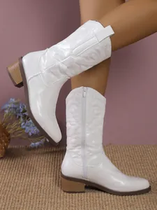 Detailed view of white Western cowboy boots with intricate embroidery and a block heel.