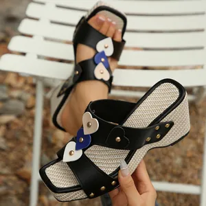 Detalle de sandalias de cuña para mujer con parches de corazón y remaches dorados