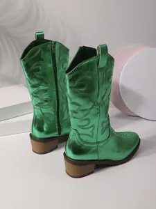 Close-up of metallic green cowboy boots featuring western embroidery and block heels