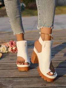 Stylish white peep-toe platform sandals with chunky heels worn on a wooden deck