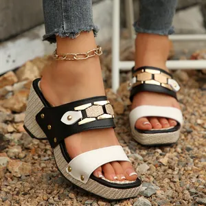 Primer plano de sandalias de cuña blancas y negras para mujer con hebillas doradas