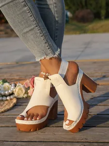 Detail view of white platform sandals with chunky brown soles and toe-loop design.