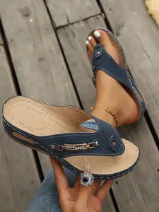 Detalle de sandalias de cuña azul marino con pedrería brillante y diseño perforado