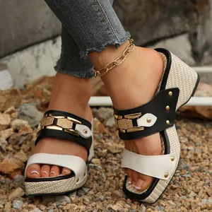 Primer plano de sandalias de cuña en blanco y negro con hebilla de metal y suela tejida