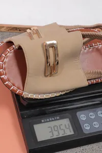 Vue détaillée d'une sandale plate beige avec brides élastiques pesée sur une balance