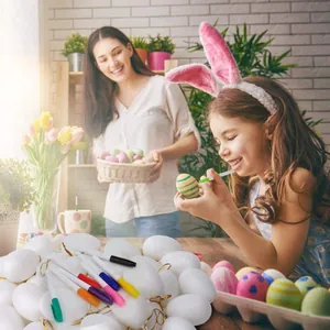 Young girl painting DIY white Easter eggs with colorful markers in a warm home craft setting