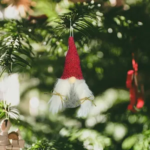 Detail of a handmade Christmas gnome ornament with a red knitted hat on a tree