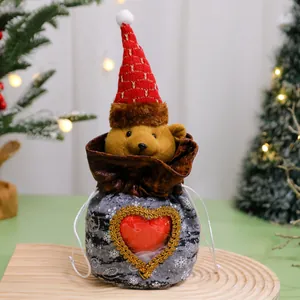 Gros plan d'un sac cadeau de Noël festif arborant un ours en peluche avec un bonnet de Noël.