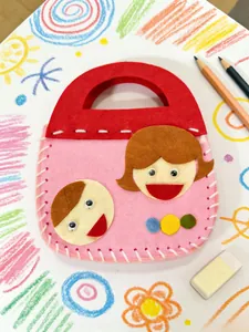Detailed view of kids' DIY handmade felt sewing bag with cute cartoon character faces