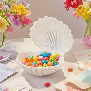 Scatola regalo a forma di conchiglia bianca con caramelle colorate su tavolo decorato