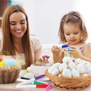Detail showing child and mother painting white DIY Easter eggs with colorful markers.