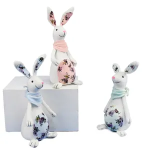 Detailed view of three fabric Easter bunny figurines with floral accents on white background