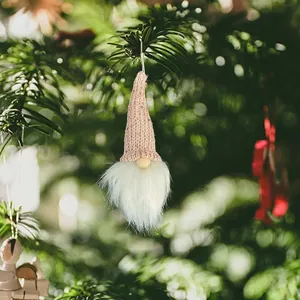Detail view of a pink knitted Christmas gnome ornament hanging on a pine tree branch
