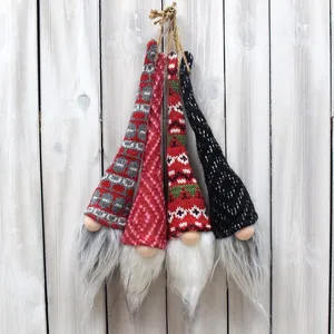 Gros plan détaillé de quatre gnomes de Noël tricotés suspendus sur un fond de bois blanc rustique