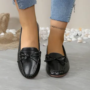 Gros plan sur des mocassins noirs pour femmes avec nœud décoratif et couture mocassin.