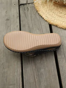 Vista detallada de chanclas con cuña negras para mujer con suela antideslizante estriada