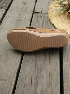 Vista detallada de la suela antideslizante de chanclas con cuña marrón para mujer.