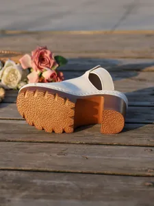 Close-up of non-slip sole and chunky high heel on white platform mules