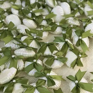 Eleganti scatole regalo a forma di conchiglia bianca con fiocchi verdi e perle per feste.