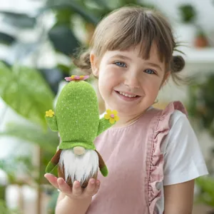 Handgefertigter Kaktus-Gnom-Plüschpuppen-Ornament von einem Kind im natürlichen Licht gehalten