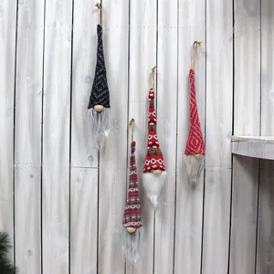 Lot de quatre gnomes de Noël tricotés à la main suspendus sur un mur en bois rustique