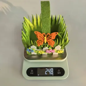 Nahaufnahme eines leichten grünen Osterkorbs aus Filz mit einem leuchtend orangen Schmetterling