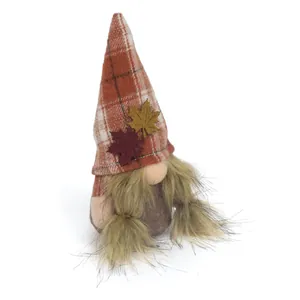 Dettaglio di uno gnomo autunnale di peluche con foglie d'acero e cappello a quadri.