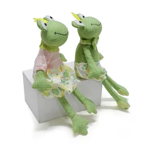 Détail de deux poupées grenouilles en tissu fait main sur un bloc d'exposition blanc