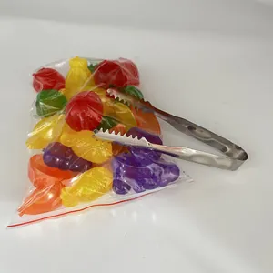 Set of colorful fruit-shaped reusable plastic ice cubes in a zipper bag with metal tongs