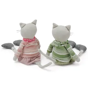 Detailed back view of two handmade cat fabric dolls wearing pink and green outfits