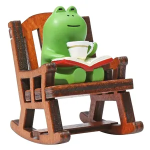 Detailed view of a cute green frog figurine reading on a wooden rocking chair for desk