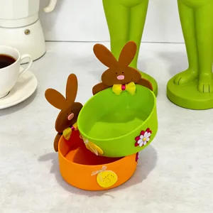 A close-up detailed view of two colorful Easter felt bunny storage baskets for candy or eggs.