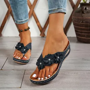 Detalle de chanclas de cuña azul marino con flores y elegantes costuras blancas